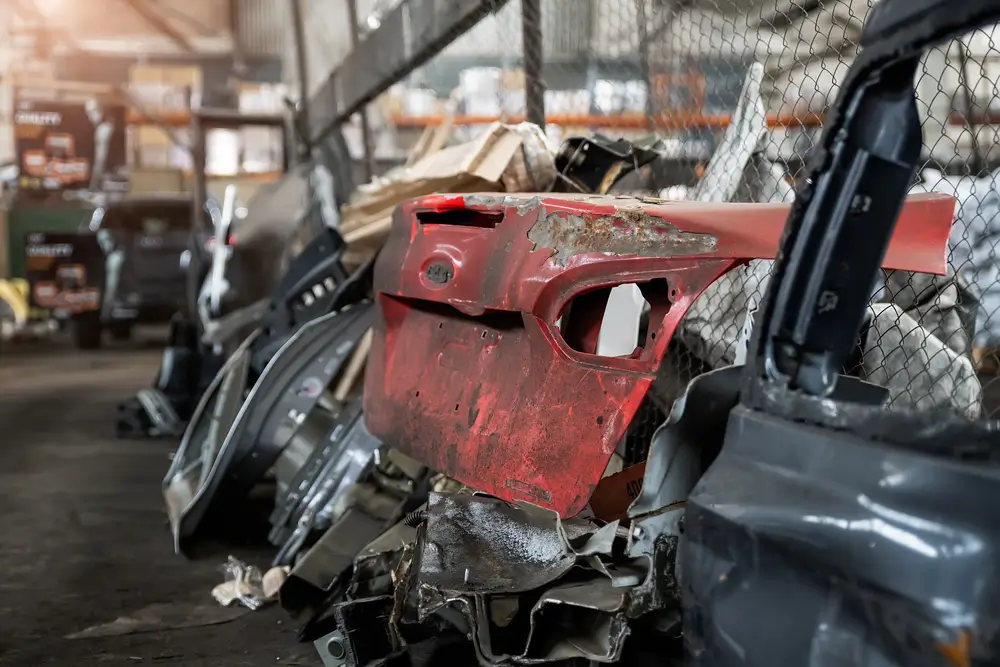 Heap of old rusty disassembled car parts at workshop waste storage hangar indoor. Vehicle salvage dismantling garage. Iron auto spare details trunk pile for recycling at scrap junkyard