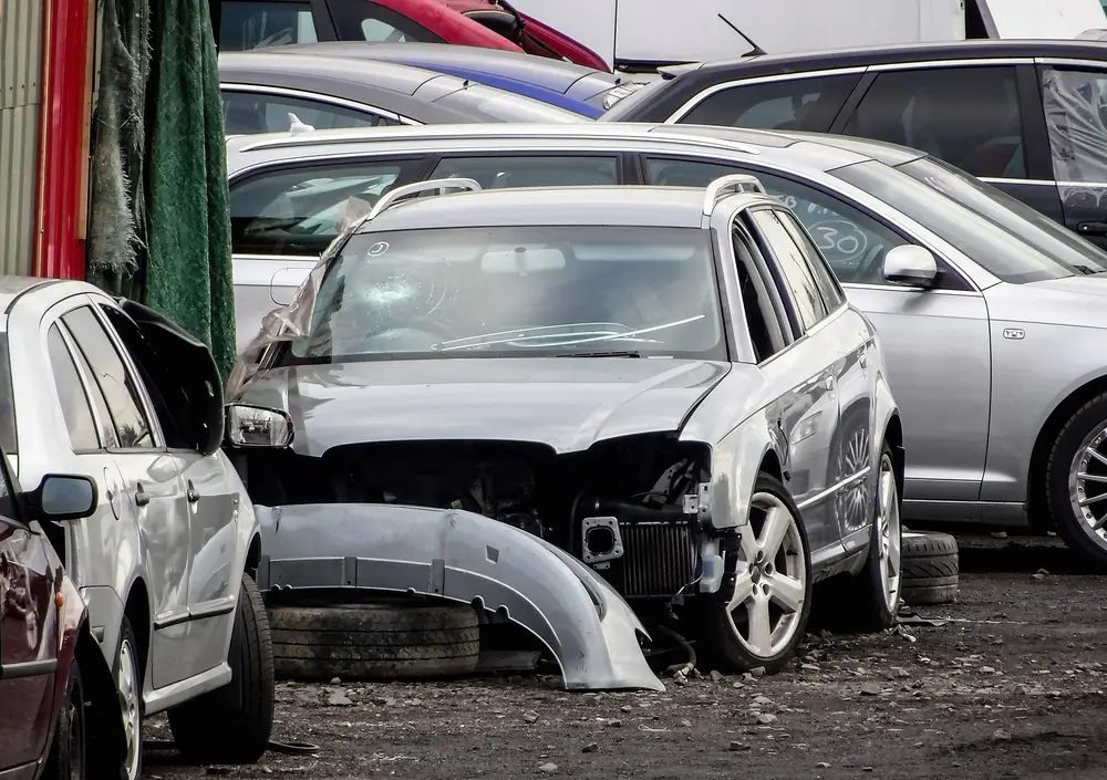 Damaged grey cars waiting in a wreckyard to be recycled or used for spare parts
